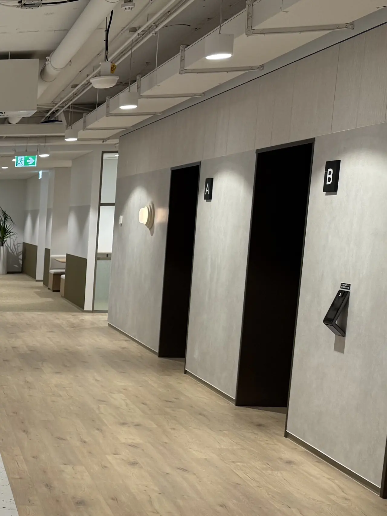 Two lift doors marked A and B off a timber floored common area corridor